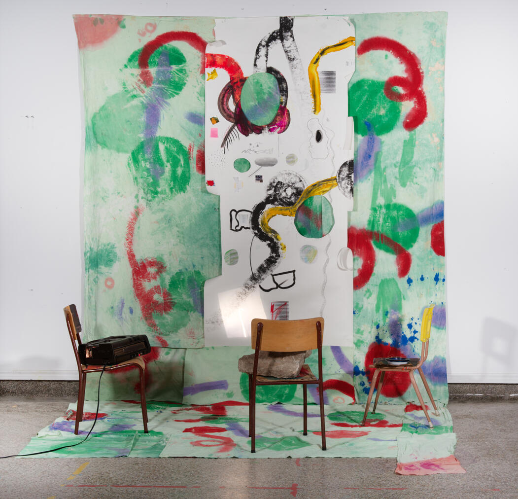 Re-imagined pedagogical landscape experiments (2024). Installation art / re-search creation: sheets, acrylic paint, ink, paper, chairs, rocks, bowl, cardboard, ink, projector (dimensions variable). Place des Artistes de Farrellton